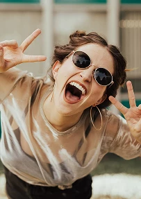 A woman in sunglasses laughing towards the camera